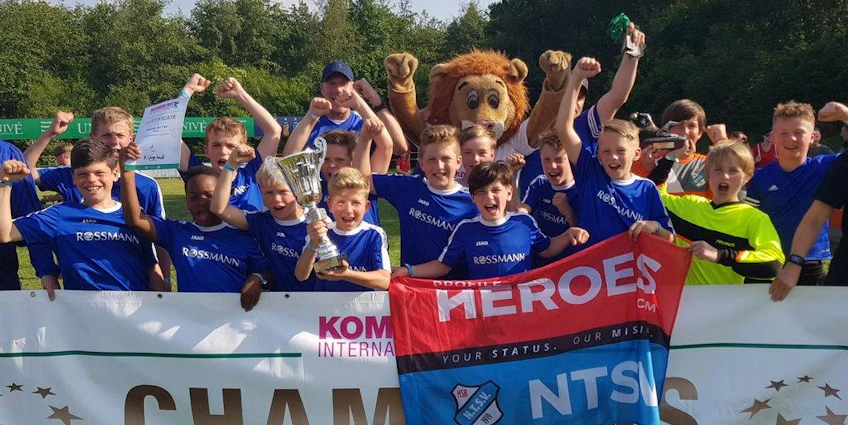 Equipe de futebol jovem comemorando a vitória com um troféu no torneio Slagharen Trophy.