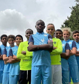 Разнообразная молодежная футбольная команда позирует уверенно на Кубок Средиземноморья.