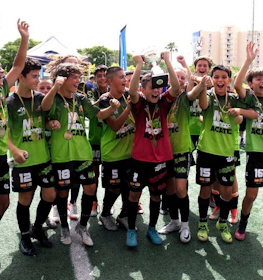 Equipe de futebol juvenil animada com troféu comemorando no Mallorca International Football Cup.