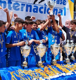 Jovens futebolistas celebrando vitória com troféus na Madrid International Cup