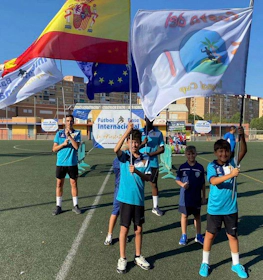 Young soccer players with Spanish and European Union flags on the field.