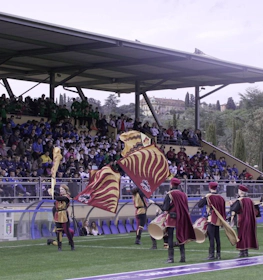 Porta-estandartes medievais se apresentando no torneio de futebol Florence Cup diante de um público.