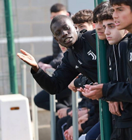 Молодые футболисты в спортивных костюмах Juventus сосредоточены на игре, один из них объясняет жестами.