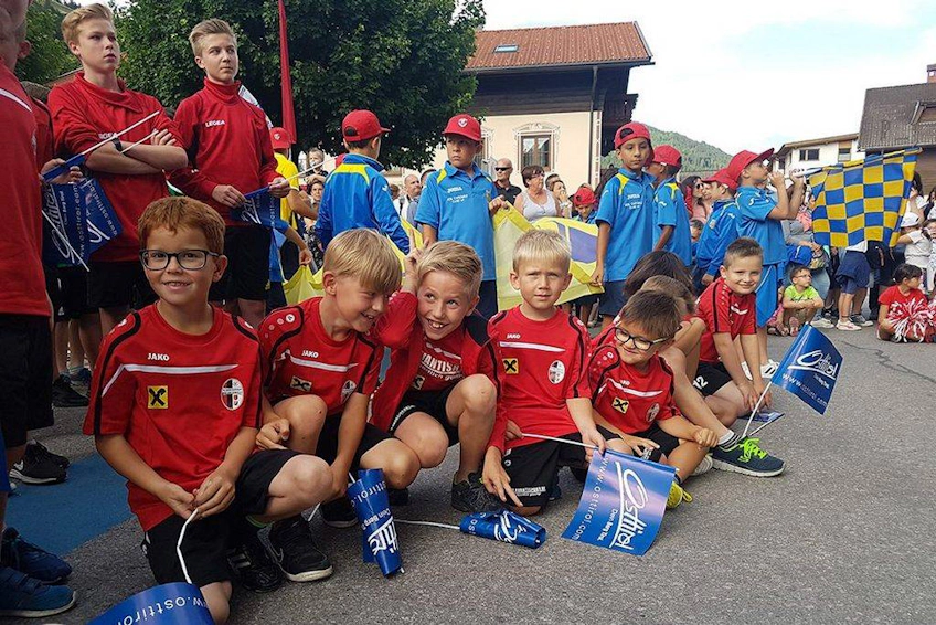Jovens jogadores de futebol em camisas vermelhas com bandeiras no festival Trofeo Città di Jesolo