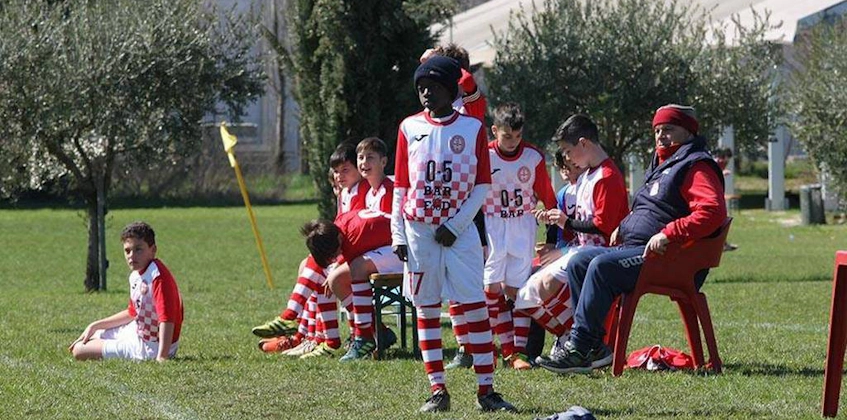 Maç sırasında kenarda dinlenen ve strateji geliştiren kırmızı-beyaz üniformalı genç futbolcular.