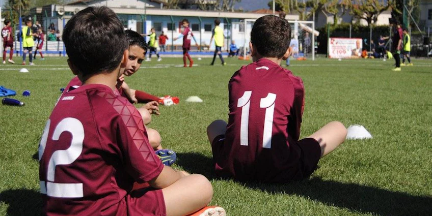 Jovens futebolistas descansando na grama no torneio de futebol Pisa World Cup