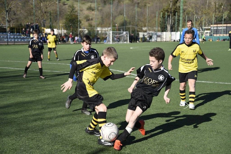 Children in black and yellow football kits playing soccer on the field
