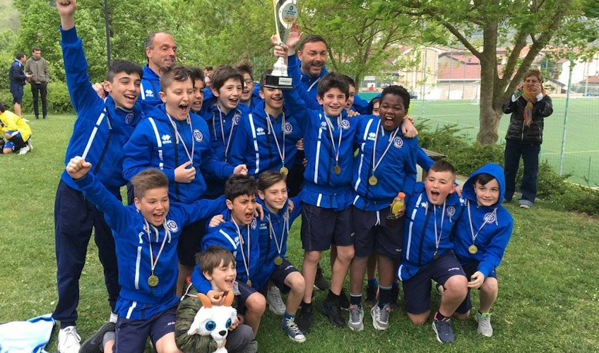 Gioiosa squadra di calcio giovanile con medaglie e un trofeo celebra la loro vittoria in un festival di calcio, con gioia e orgoglio.