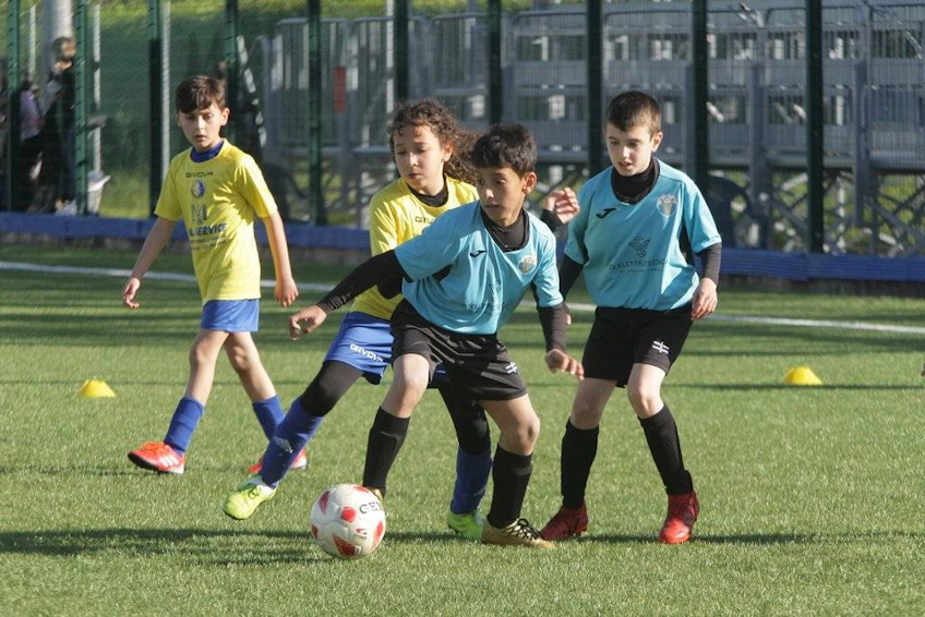 Jovens futebolistas com camisas amarelas e turquesas jogando no torneio Trofeo Città di Viareggio