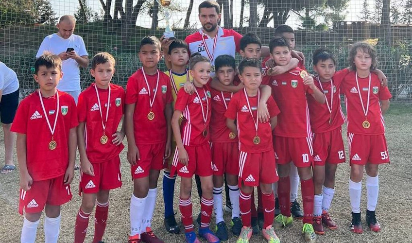 Детская футбольная команда в красных формах с медалями на турнире в Анталии
