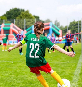 Jogadora de futebol número 22 com camisa verde chutando durante o torneio Laola Cup