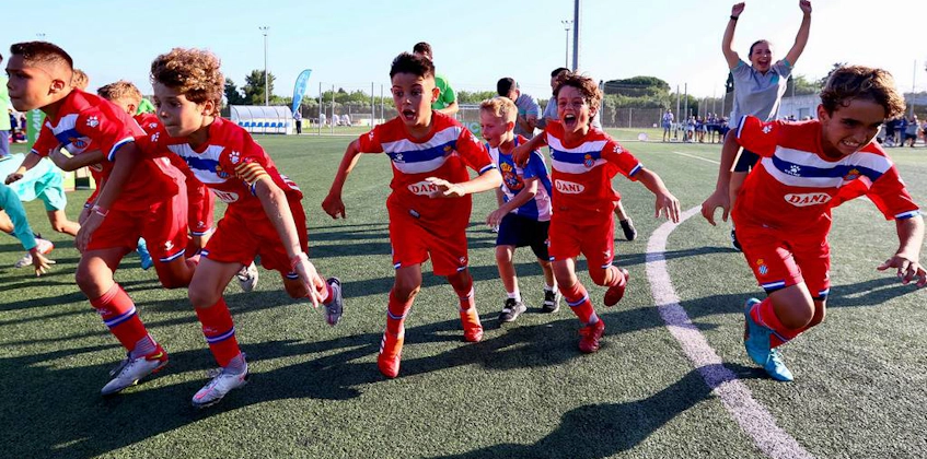 Радостные молодые футболисты в красно-синих формах празднуют на турнире MICFootball 7