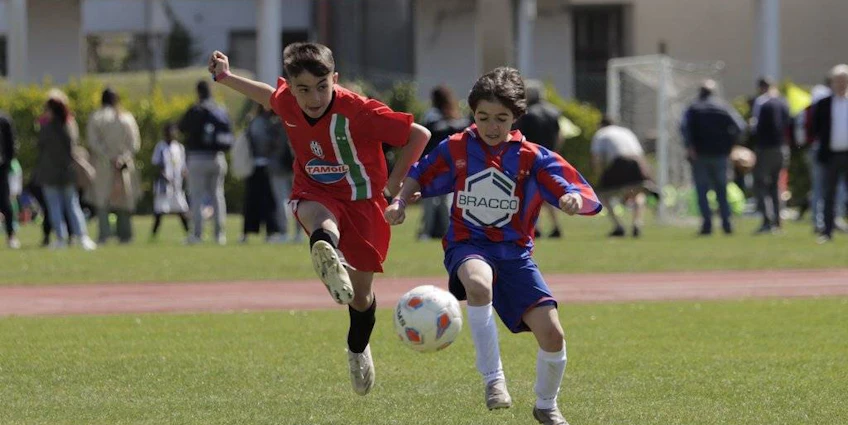 Deux jeunes joueurs de football en maillots rouge et bleu-rouge se disputant le ballon