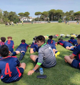 Mavi ve kırmızı formalarıyla genç futbol takımı bir maçı izliyor