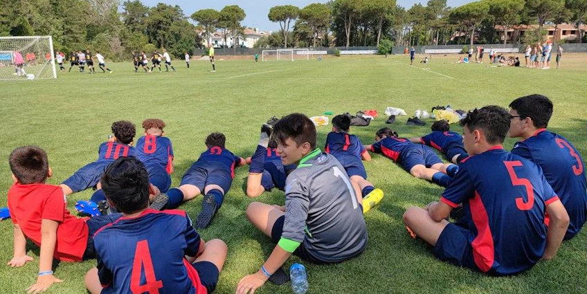 Молодежная футбольная команда в синих и красных формах наблюдает за игрой
