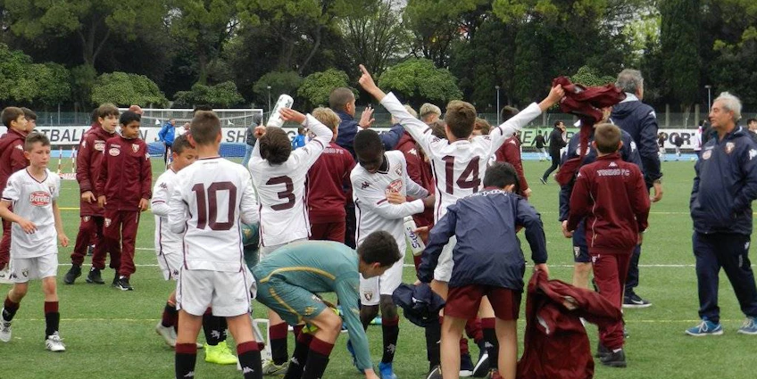 Jeunes footballeurs célébrant une victoire en tournoi, entraîneurs et joueurs en arrière-plan