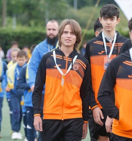 Jovens futebolistas em agasalhos laranja e preto no torneio Xixón Esei Cup
