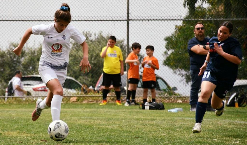 Юная футболистка управляет мячом на турнире Ayia Napa Youth Soccer Festival