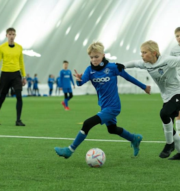 Crianças vestindo roupas esportivas jogando futebol no torneio iSport February Cup