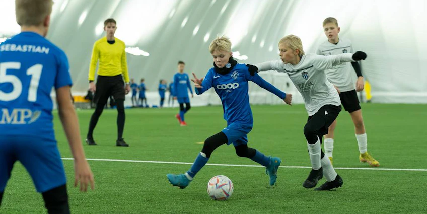 Crianças vestindo roupas esportivas jogando futebol no torneio iSport February Cup
