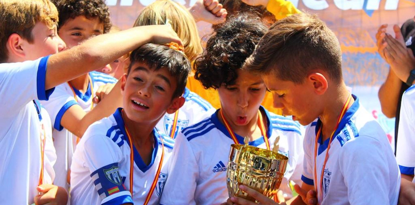 Jovens futebolistas beijando o troféu no torneio Mediterranean Esei Cup
