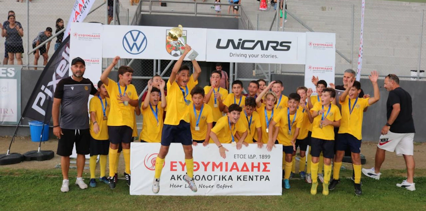 Equipe de futebol juvenil comemorando uma vitória no torneio Platres Summer Football Festival