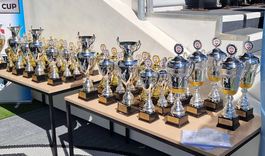 Коллекция футбольных трофеев, выставленных на столе на футбольном турнире