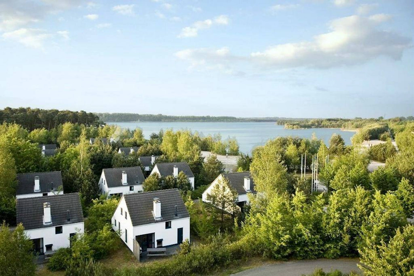 Oostduinkerke'de göl kenarında yeşil ağaçlar arasında beyaz evler