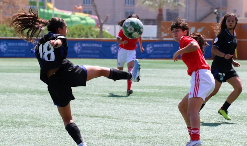 Женские футболисты в действии, одна бьет по мячу в воздухе во время игры