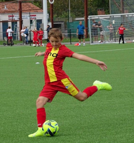 Garçon en tenue rouge donnant un coup de pied dans un ballon de foot à la Ixina Cup