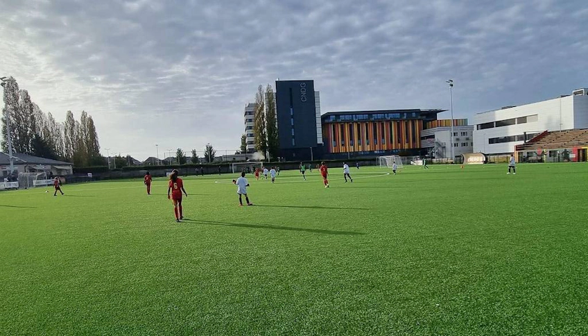 Binaların arka planında yeşil sahada Scimemi Kupası futbol turnuvası oyuncuları