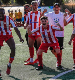 Soccer players in red and white striped uniforms celebrating a win on the field