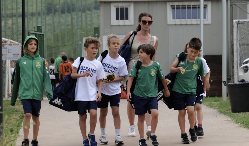 Bir oyun sonrası antrenörleriyle yürüyen futbol ekipmanlı çocuklar