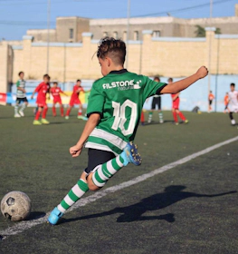 Joueur junior numéro 10 en vert frappant le ballon au tournoi U14 KHS Cup
