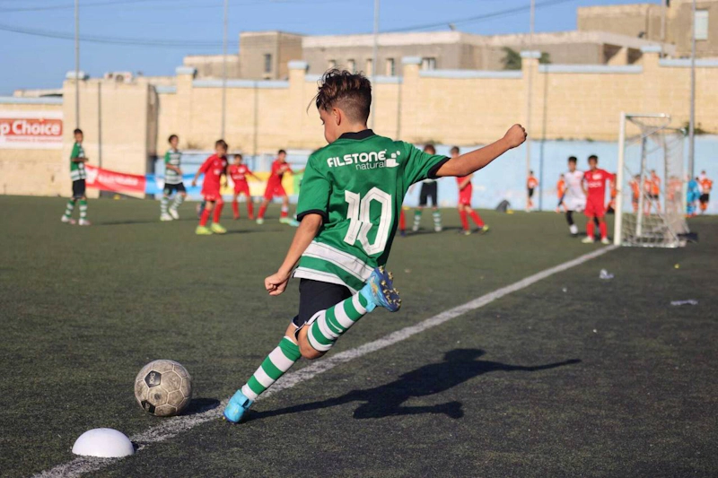 Юноша в зеленой форме номер 10 ведет мяч на турнире U14 KHS Cup