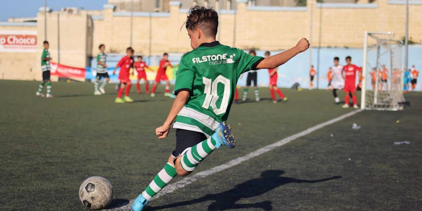 身穿10号绿色球衣的青少年在U14 KHS杯足球赛中踢球