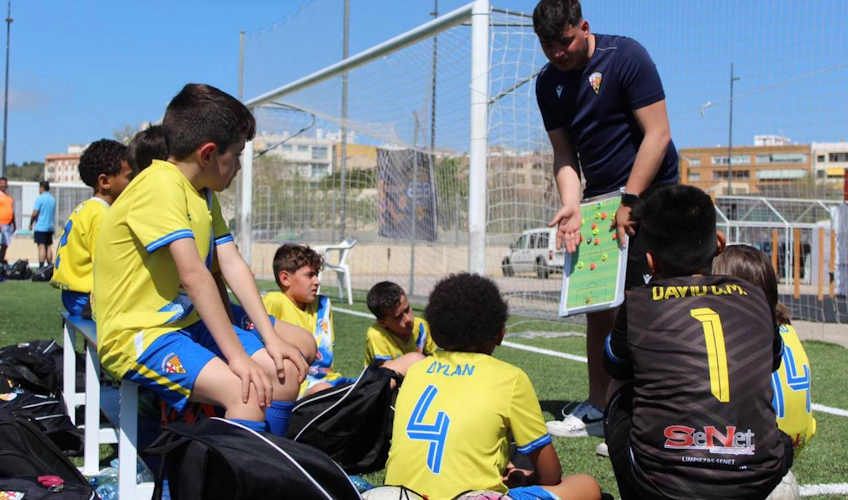Antrenör, Sun Esei Cup futbol turnuvasında sahada çocuklara eğitim veriyor