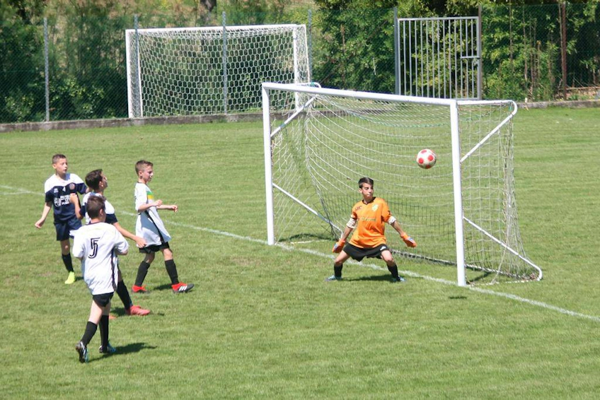Детский футбольный матч, вратарь в оранжевой форме готовится отразить гол.