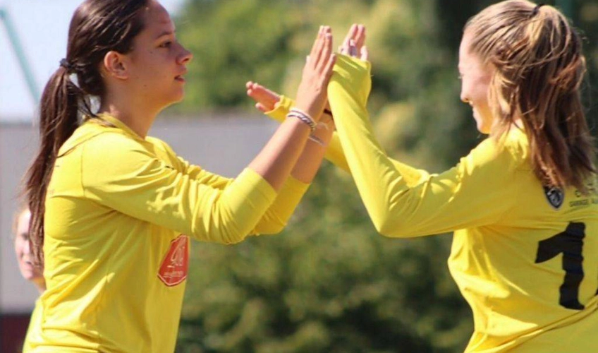 Две девушки в жёлтых футбольных формах чествуют друг друга на турнире