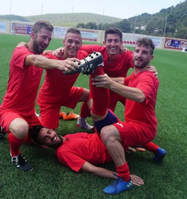 Kırmızı formaya sahip futbol takımı Ibiza Football Fun turnuvasında zaferi kutluyor