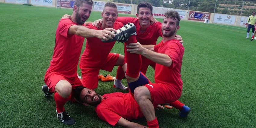 Футбольная команда в красной форме радуется победе на турнире Ibiza Football Fun