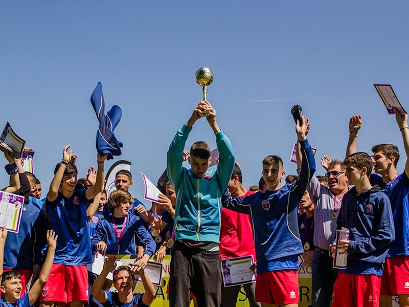 Football team celebrating victory with trophy at Salonica Soccer Cup