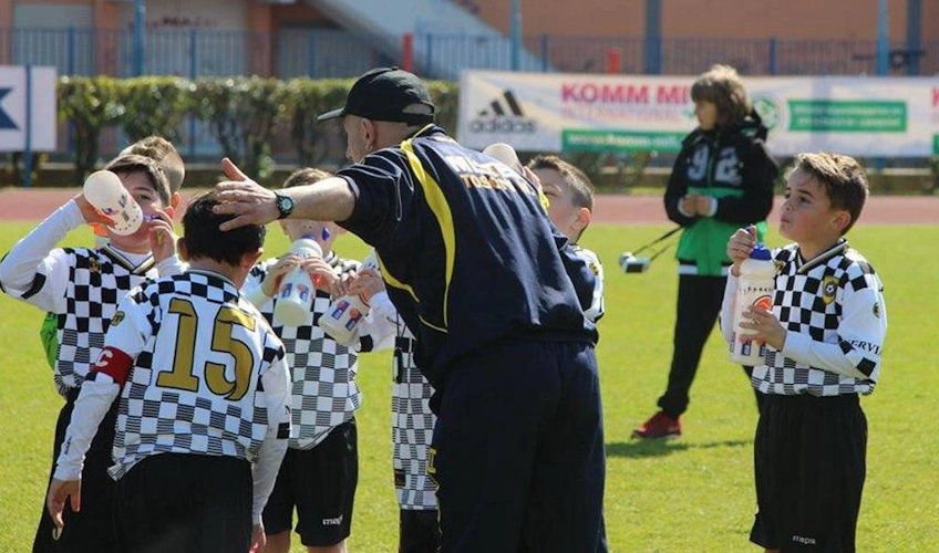 Тренер раздает воду юным футболистам на турнире Istria Cup