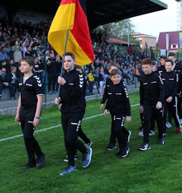 Equipa de futebol jovem com bandeira a liderar desfile no estádio