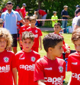 Young footballers in red kits walking on the pitch at the Pyrenees Cup tournament.