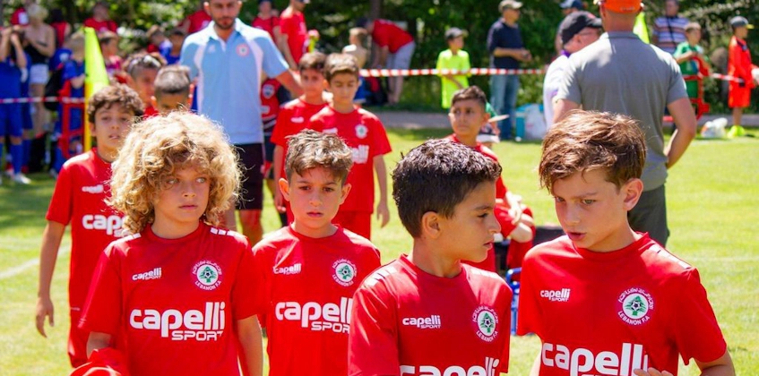 Kırmızı formalarıyla genç futbolcular Pyrenees Cup turnuvasında sahada yürüyor.